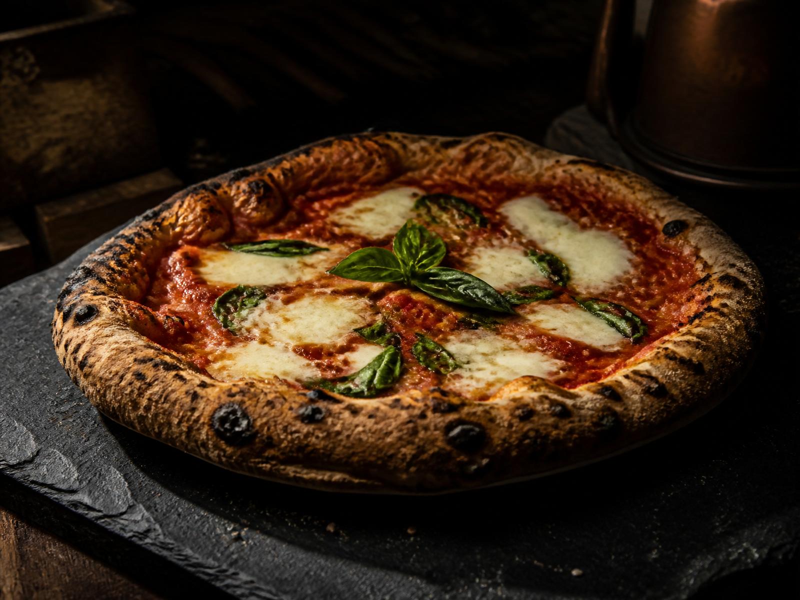 Wood-fired margherita pizza on a slate board